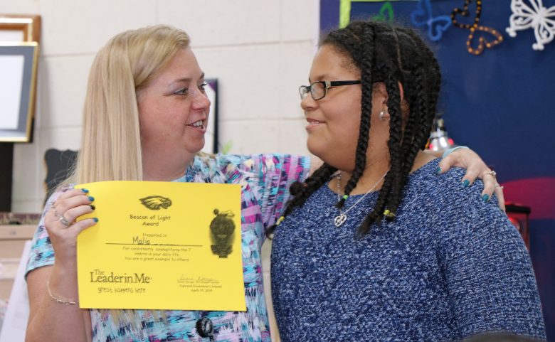 Student receives leadership award from teacher.