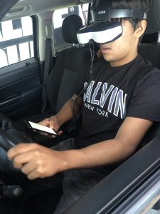 Student with virtual reality goggles does a driving simulation.