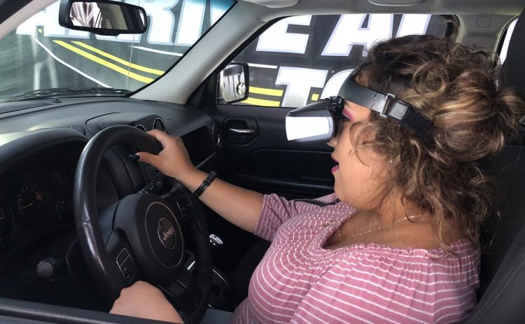 Student with virtual reality goggles does a driving simulation.
