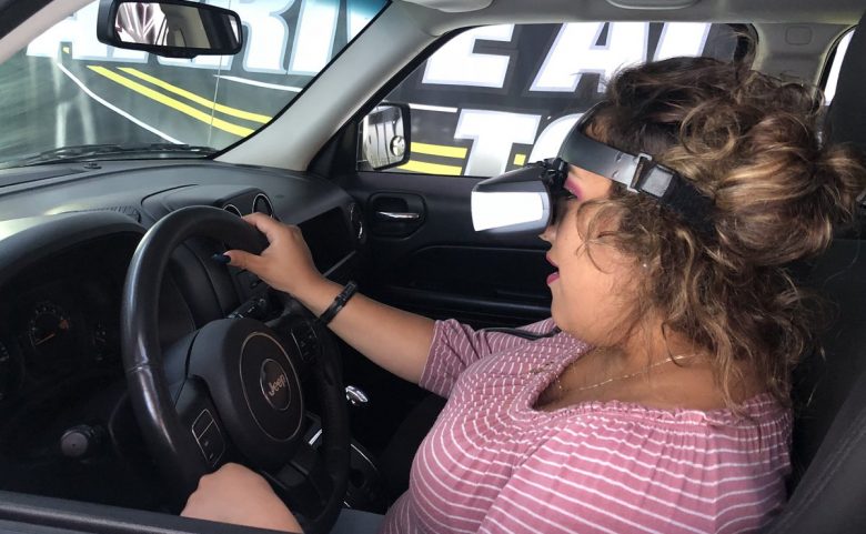 Student with virtual reality goggles does a driving simulation.