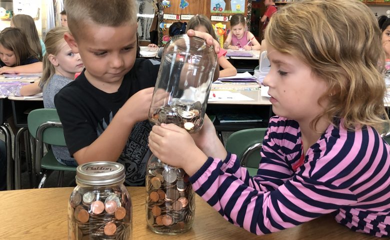 Students transfer change to a mason jar.