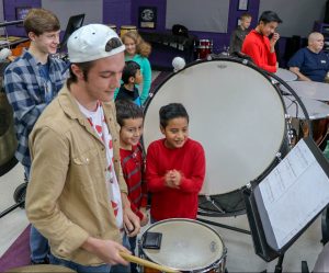 elementary boys watch high schooler play drums