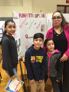 3 students and parent with science project display board