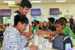 3 students at lunch table stacking cups