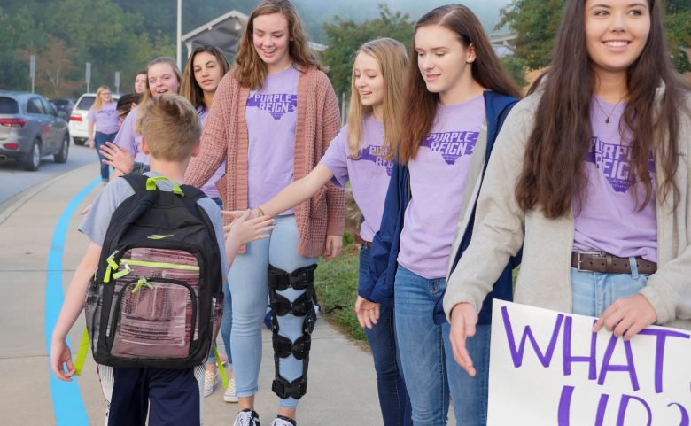 6 high school girls high fiving an elementary student