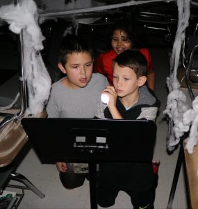 3 boys using flashlight to read