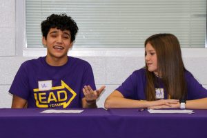 2 students at purple table, smiling