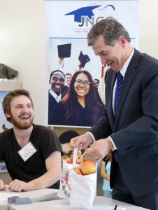 Student smiles as governor receives apples