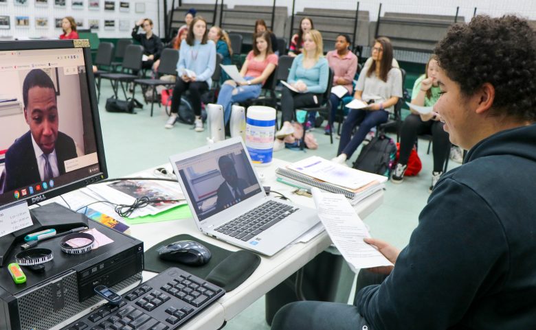 student video chatting with composer, with group in background