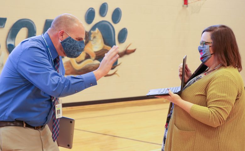Principal Mark Page (L) waves to Atkinson staff and students who joined in virtually on the celebration, thanks to behind-the-scenes work from Amanda Childers, Small Schools Administrator.