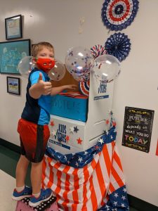 elementary student gives thumbs up while dropping vote in ballot box