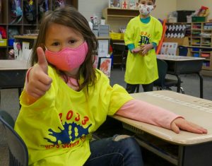 kindergartener in neon yellow shirt giving thumbs up