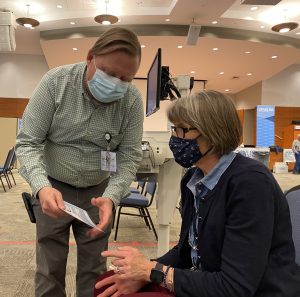 man advising woman about her next appointment for COVID vaccine