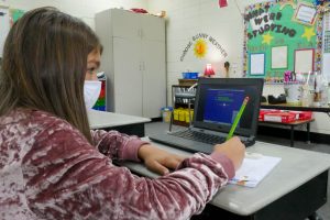 girl at desk with pencil in hand on computer