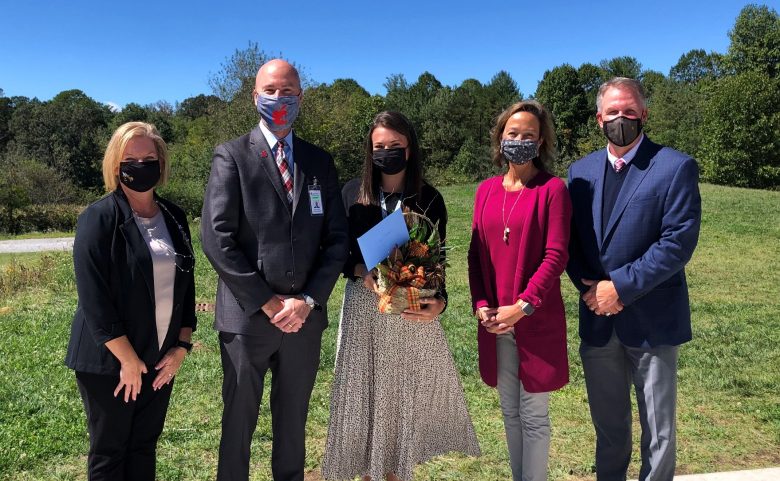 five people standing outside in masks