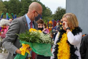 woman wiping tear from eye while man gives her flowers