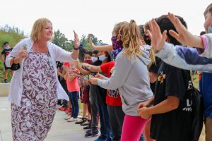 line of students reaching to high five principal