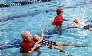 swim teacher helping a student float