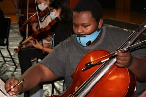 student with cello making notes on music