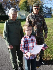 student outside reading poem with grandparents in military uniform standing behind