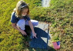 2nd grader Siona Hayes reads the inscription of a Veteran's gravesite