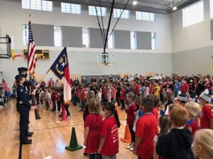 high school students in color guard present flags for elementary school assembly