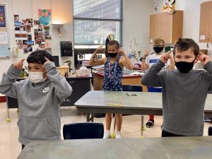 four students practicing sign language inside classroom 