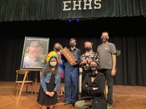 six people on high school stage holding props