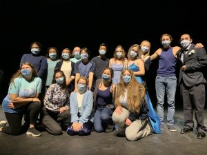 16 students posed on stage in masks