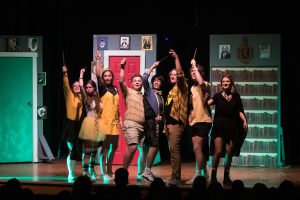 photo of 8 students on a stage, raising wands