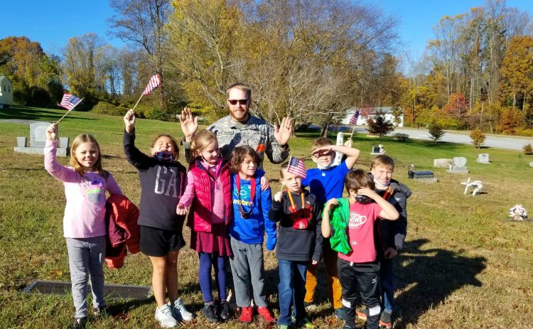 group of 2nd graders standing outside in cemetery with veteran