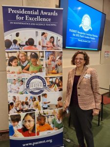 woman standing next to banner that reads "Presidential Awards for Excellence"