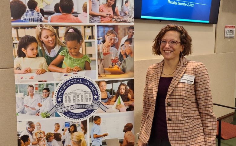 woman standing next to banner that reads "Presidential Awards for Excellence"