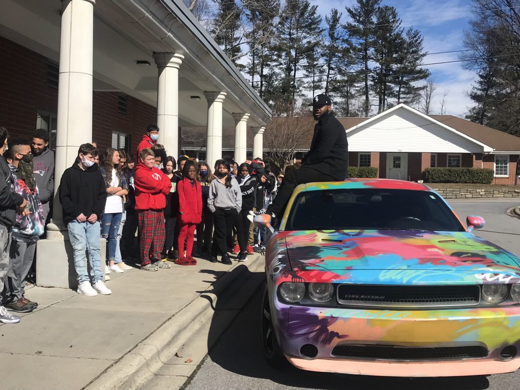 colorful car in front of school with students standing around