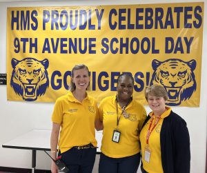 three women in yellow in front of sign