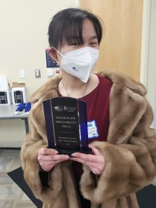 student in mask holding plaque