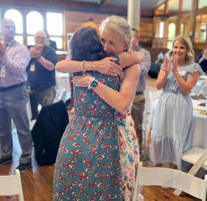 two women hugging as people in background clap