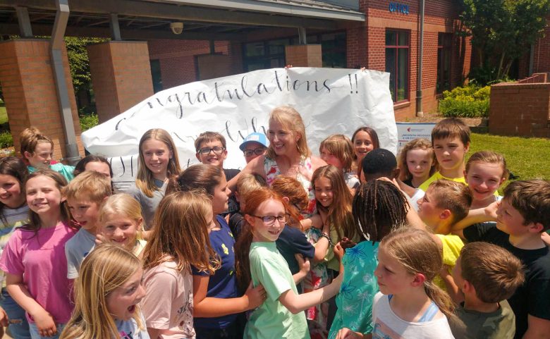 woman outside surrounded by students with banner behind