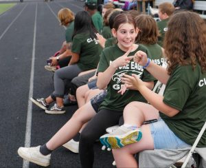 elementary students playing "rock paper scissors" on high school track