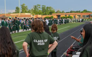 kids i n"Class of 2029" shirts watching graduates walk by