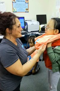 Teacher assisting student with new t-shirt