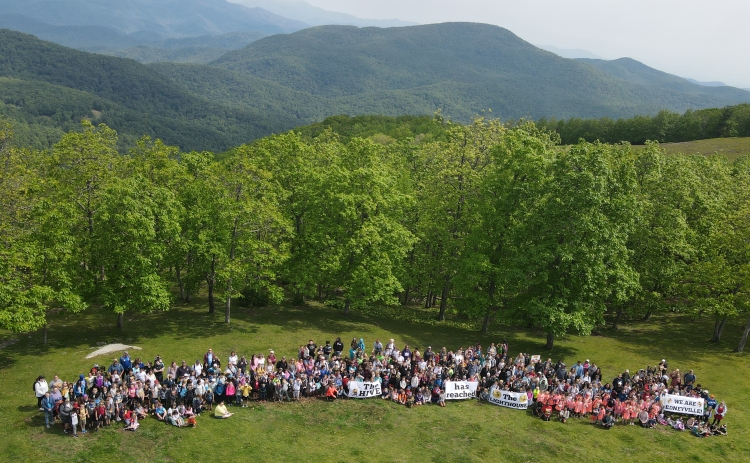 Students standing in front of a mountain celebrating getting Lighthouse status.