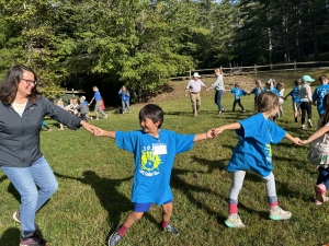 Students and teachers holding hands in a big circle while learning square dancing. 