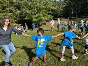 Students and teachers holding hands in a big circle while learning square dancing.