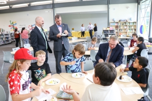 Several students eating cake in the library with the superintendent Mark R. Garrett, Carl Taylor, and Scott Rhodes.