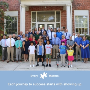 A group photo of the 23 school principals, district leadership team, and five students. There is text that says "Every Piece Matters. Each journey to success starts with showing up." 