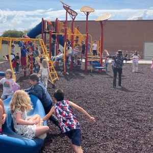 Over two dozen students playing on the playground at Upward Elementary School. 