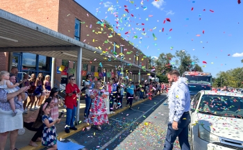 Dr. John McDaris arriving to the Rugby with confetti in the air. Students and teachers in the background of the photo.