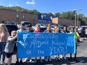 Eight students holding a sign that says "Congratulations Dr. McDaris Principal of the Year!"