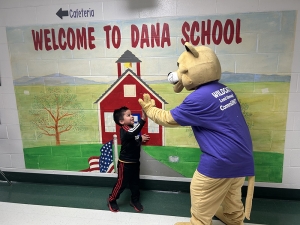 The Dana mascot and a student high-five in the hallway